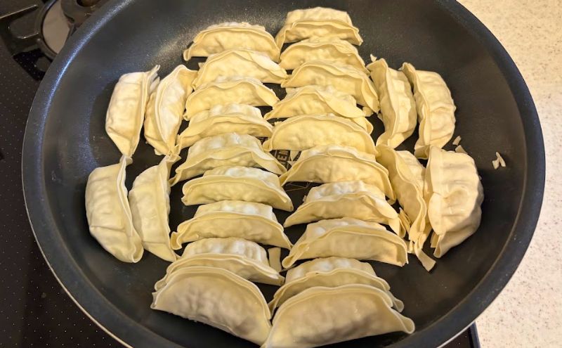 フライパンに並べた焼く前のコープデリの冷凍餃子